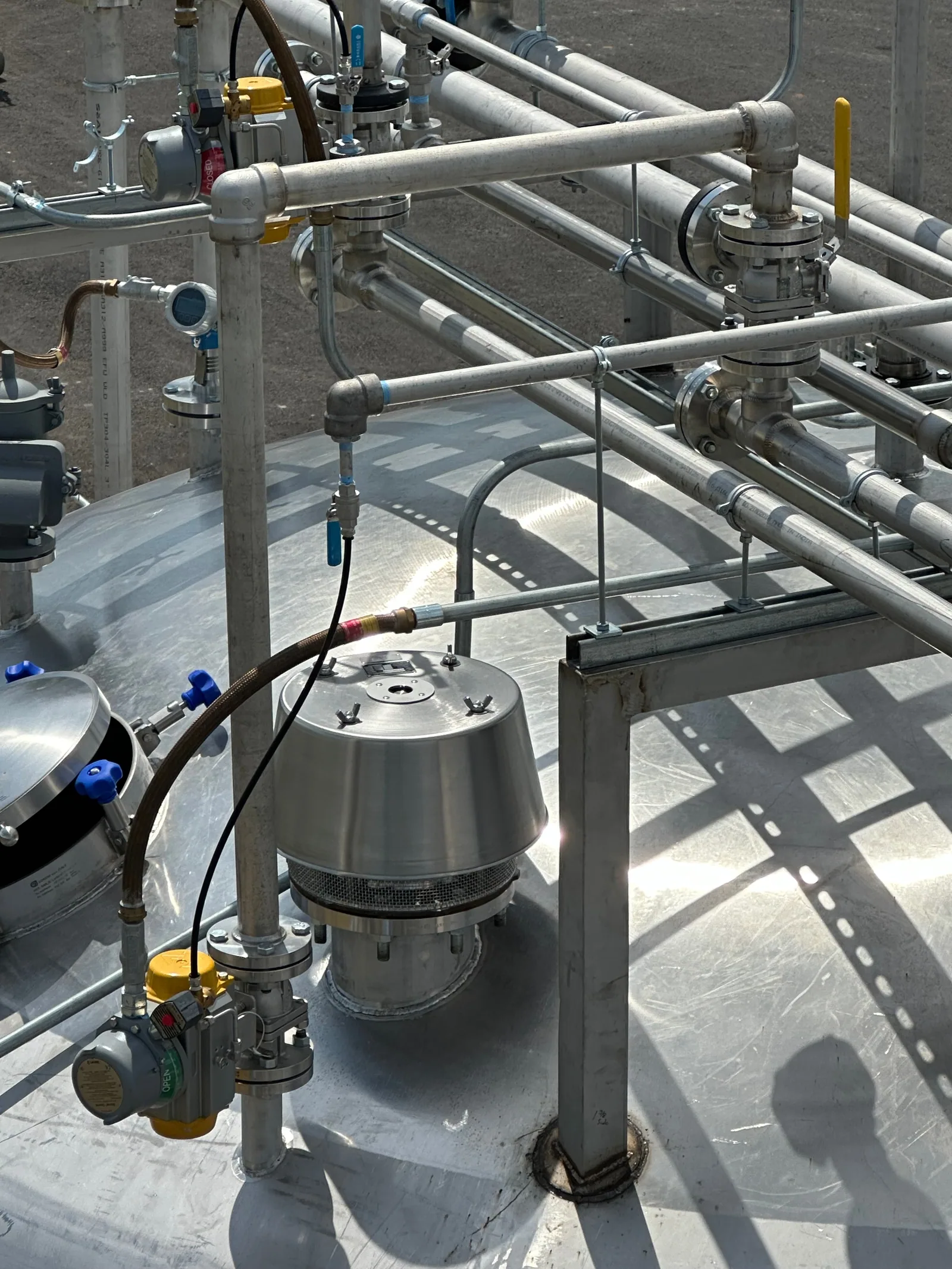 A conservation vent valve mounted on top of a tank with piping and fittings around it.