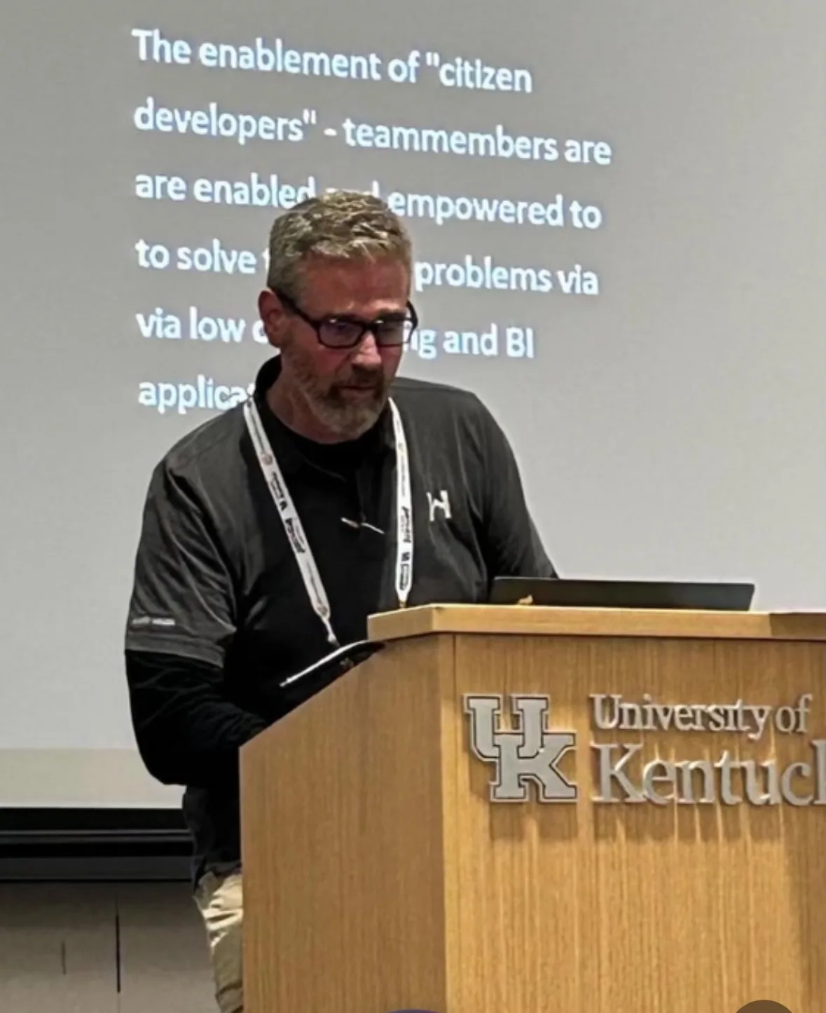 Roger Henley speaking at a podium in a lecture hall at the University of Kentucky.