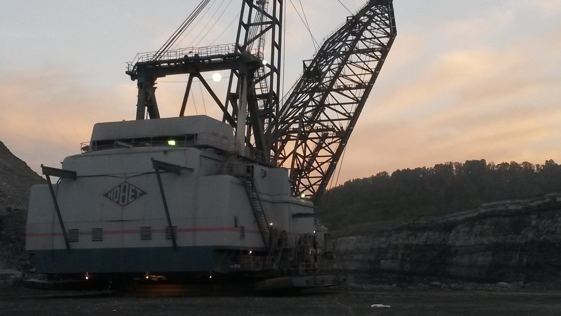 A dragline excavator at Hobet Mining at dusk, its boom silhouetted against the sky over a stripped bench.